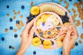 Berry greek yoghurt with frefh blueberries, banana and flakes in the pink bowl on the blue wooden table Royalty Free Stock Photo