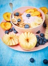 Berry greek yoghurt with frefh blueberries, banana and flakes in the pink bowl on the blue wooden table Royalty Free Stock Photo