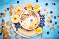 Berry greek yoghurt with frefh blueberries, banana and flakes in the pink bowl on the blue wooden table Royalty Free Stock Photo