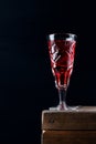 Berry liquor in crystal vintage shot glass on black