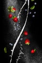 Berry mix. Fresh ripe strawberries and blueberries in flight on a black background Royalty Free Stock Photo