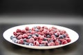 A Berry mix  from frozen raspberries and blueberries on the white plate. A Frozen Berries in black background.  A sweet background Royalty Free Stock Photo