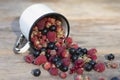 Berry mix scattered out iron mug on wood table. Summer Vitamin. Garden morsel Royalty Free Stock Photo