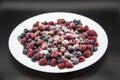 A Berry mix in sugar from frozen raspberries and blueberries on the white plate. A Frozen Berries with Sugar.  A sweet background Royalty Free Stock Photo