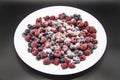 A Berry mix in sugar from frozen raspberries and blueberries on the white plate. A Frozen Berries with Sugar.  A sweet background Royalty Free Stock Photo