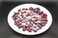 A Berry mix in sugar from frozen raspberries and blueberries on the white plate. A Frozen Berries with Sugar.  A sweet background Royalty Free Stock Photo