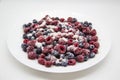 A Berry mix in sugar from frozen raspberries and blueberries on the white plate. A Frozen Berries with Sugar.  A sweet background Royalty Free Stock Photo