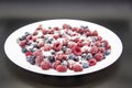 A Berry mix in sugar from frozen raspberries and blueberries on the white plate. A Frozen Berries with Sugar.  A sweet background Royalty Free Stock Photo