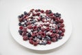 A Berry mix in sugar from frozen raspberries and blueberries on the white plate. A Frozen Berries with Sugar.  A sweet background Royalty Free Stock Photo