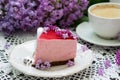 A berry mousse cake with chocolate base and juice jelly, decorated with lilac flowers, served with coffee