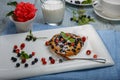 Berry muffin with blueberries and strawberries on a white plate and a wooden table served with milk and pink rose in a Royalty Free Stock Photo