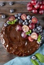 Berry pie on  blue towel,  round chocolate homemade cake with fresh blueberries and red grapes, mint on a wooden brown background Royalty Free Stock Photo