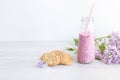Berry smoothie in a glass jar with a straw for cocktails, cereal cookies, a branch of lilac, on a light background. Healthy lifest