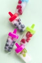 Berry summer ice lolly with raspberries, blueberries, mint leaves on a green mint background