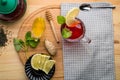 Berry tea in a cup near lemon, honey, lemon balm, ginger and a teapot on a table on a round wooden stand top view. Royalty Free Stock Photo