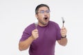 A bespectacled middle aged man looking in disbelief and shock while looking at something mouthwatering. Holding a fork and spoon Royalty Free Stock Photo