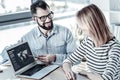 Bespectacled pleasant man sitting and demonstrating program. Royalty Free Stock Photo