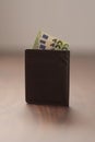 Bespoke brown all leather wallet on walnut table with euro cash