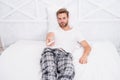 Best alternatives to cable TV. Handsome man in pajamas with remote control. Guy watching television in bedroom. Watch Royalty Free Stock Photo