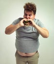 This is the best burger ever. Studio shot of an overweight man biting into a burger.