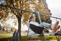 The best childhood is a fun-filled one. a little girl playing on a swing at the park with her mother in the background.