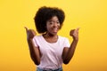 Best choice. Happy african american lady showing thumbs up gesture with both hands, posing on yellow studio wall Royalty Free Stock Photo