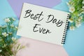 Best Day Ever text written on notepad with flowers decorations flat lay on multicolor pastel background Royalty Free Stock Photo