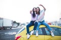 Best female friends cheering by car road trip at sunset. Happy people outdoor on vacation tour