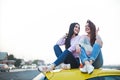 Best female friends cheering by car road trip at sunset. Happy people outdoor on vacation tour