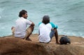 Best friends having a casual conversation on a rock on the beach