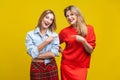 Best friends joking. Portrait of two happy women in stylish casual clothes. indoor studio shot isolated on yellow background Royalty Free Stock Photo