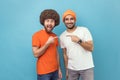 Two young adult men pointing finger each other and looking at camera with positive joyful expression Royalty Free Stock Photo