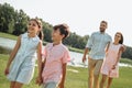 We are the best friends Two cute little children holding hands and smiling while walking on green grass with parents Royalty Free Stock Photo