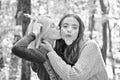 Best friends walk at autumn forest. Beautiful blonde girl kissing her bff. Brunette funny crazy girl holding fall oak