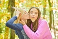 Best friends walk at autumn forest. Beautiful blonde girl kissing her bff. Brunette funny crazy girl holding fall oak