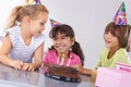 Best friends from a young age. three friends at a birthday party smiling with a cake in front of them. Royalty Free Stock Photo
