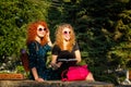 Best girlfriends are reading a notebook in a park.