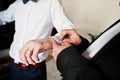 Best man helped stylish groom wear cuff links at wedding day.