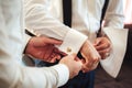Best-man helping groom to dress. Close up of hands of both men and groom`s golden propeller cufflinks in shirt sleeves Royalty Free Stock Photo