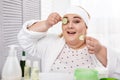Cheerful fat woman making a cucumber mask