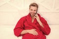 The best phone for keeping in touch. Happy man talking on mobile phone in bed. Handsome caucasian guy smiling during his Royalty Free Stock Photo