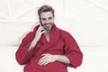 The best phone for keeping in touch. Happy man talking on mobile phone in bed. Handsome caucasian guy smiling during his Royalty Free Stock Photo