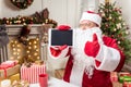 Joyful Santa Claus showing digital device as gift Royalty Free Stock Photo