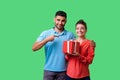 Best present for her. Portrait of happy couple in casual wear with gift box. isolated on green background