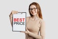 BEST PRICE. Beautiful young business woman wearing glasses holds a clipboard with mock up space isolated on gray background Royalty Free Stock Photo