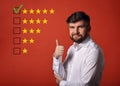 The best rating, evaluation, online rewiew. Happy bearded business showing the hand thumb up in white shirt on red background wi