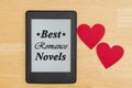 Best Romance Novels text on an e-reader on a wood desk with two hearts Royalty Free Stock Photo