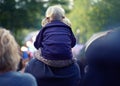 Best seat in the house. A little girl sitting on her fathers shoulders at an outdoor event. Royalty Free Stock Photo