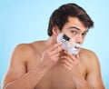 The best shave a man can get. a young man shaving his face against a studio background.