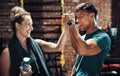 The best tag team in town. two cheerful young sportspeople cheering while working out in a gym.